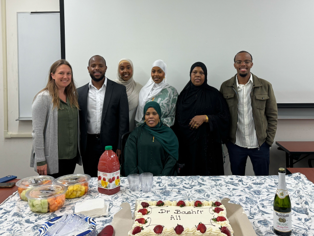 Brooke with Bashir and his family in front of table of food